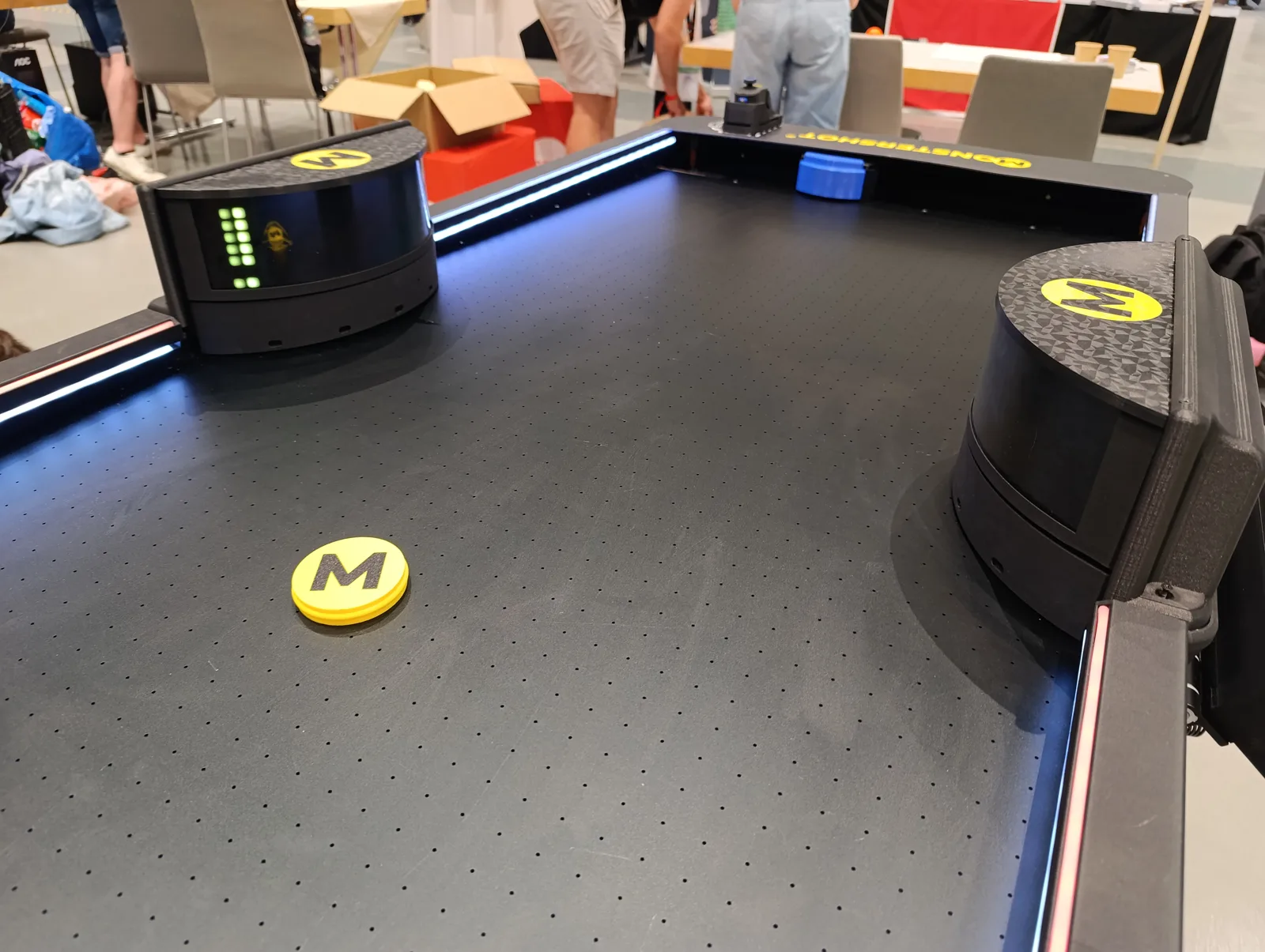 Zwei automatische Bumper mit gelbem M-Logo auf dem Monstershot®-Spielfeld, davor der gelbe Puck