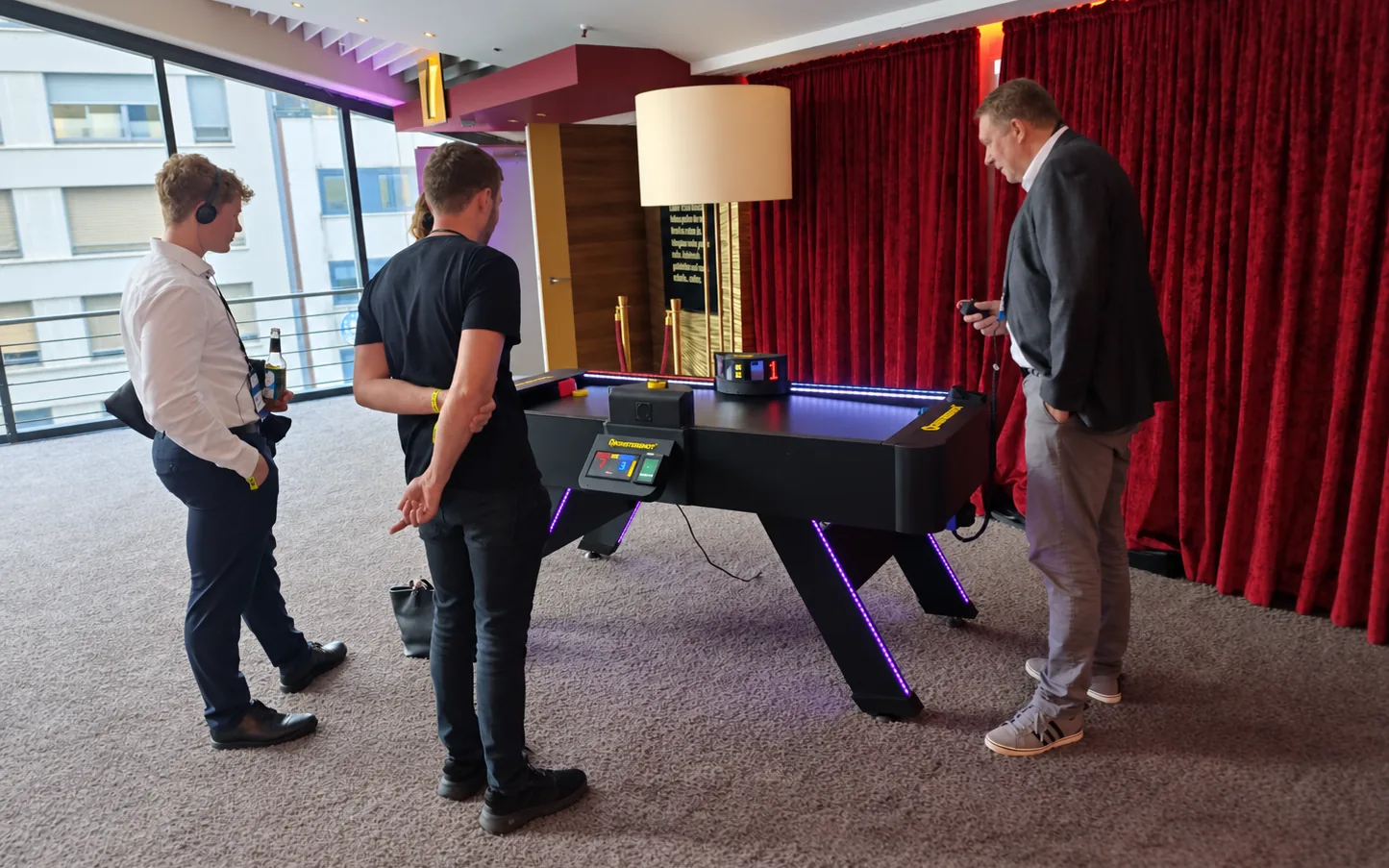 Monstershot®-Spieltisch bei Hannover Unleash, drei Besucher stehen am Tisch vor rotem Vorhang