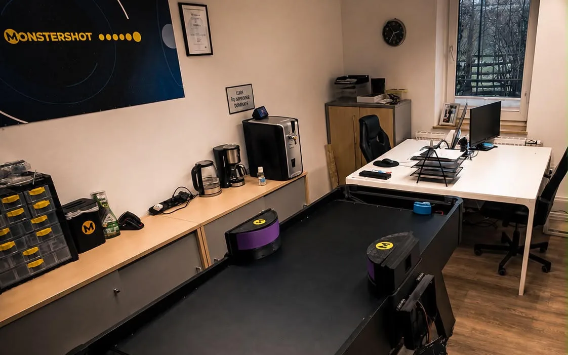 Das Monstershot®-Büro: Spieltisch, Schreibtische und Monstershot®-Banner an der Wand