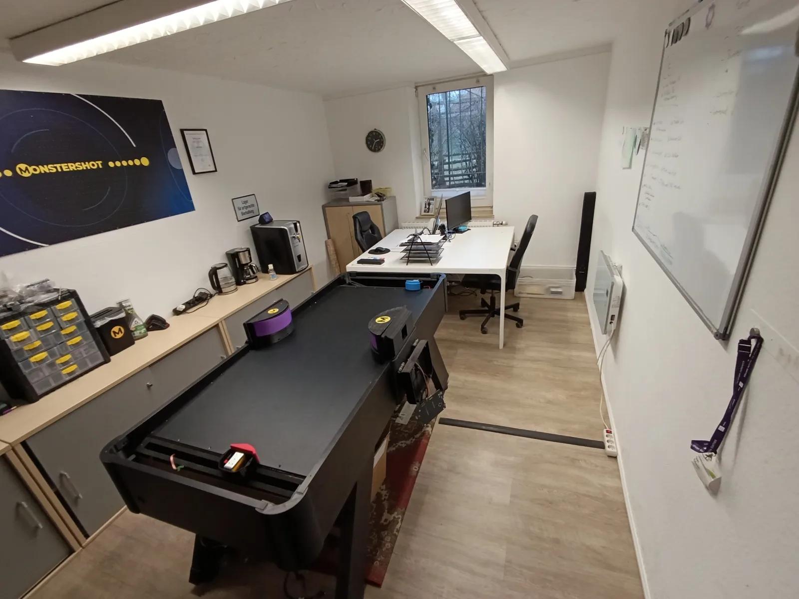 Das Monstershot®-Büro mit Spieltisch, Werkzeugwand und Monstershot®-Banner an der Wand