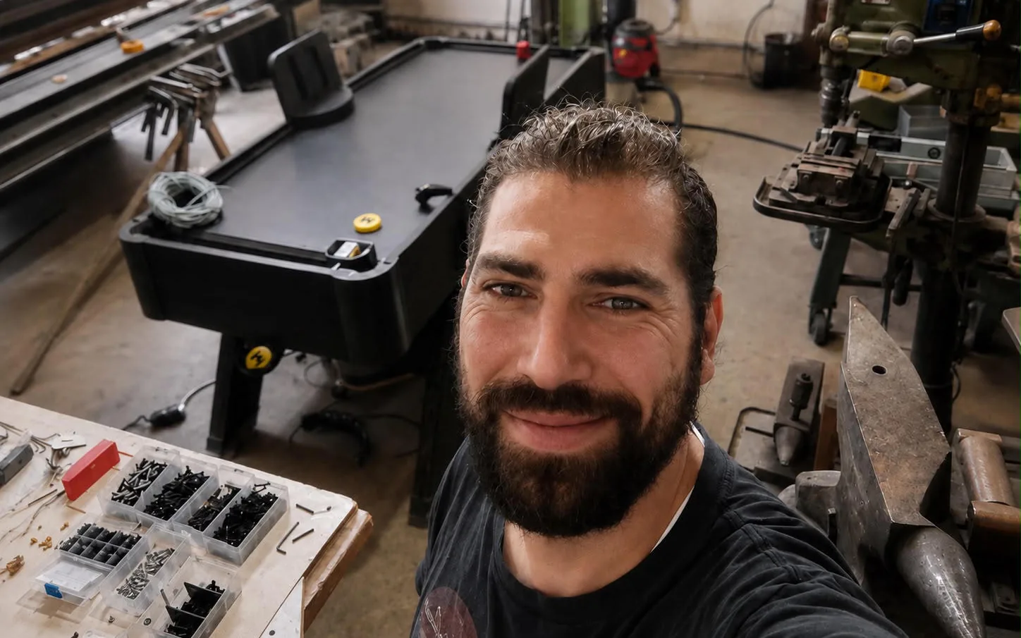 Selfie von Mitgründer Maan in der Werkstatt, dahinter ein fertiger Monstershot®-Tisch